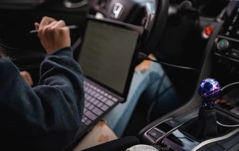 Person on a car with a laptop and a pen