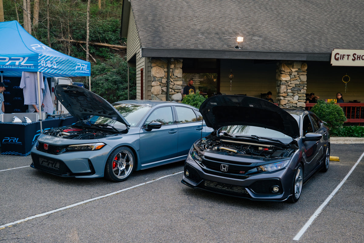 Two PRL Motorsports shop cars, a Civic Type R and a Civic Si, parked with hoods up beside the PRL tent
