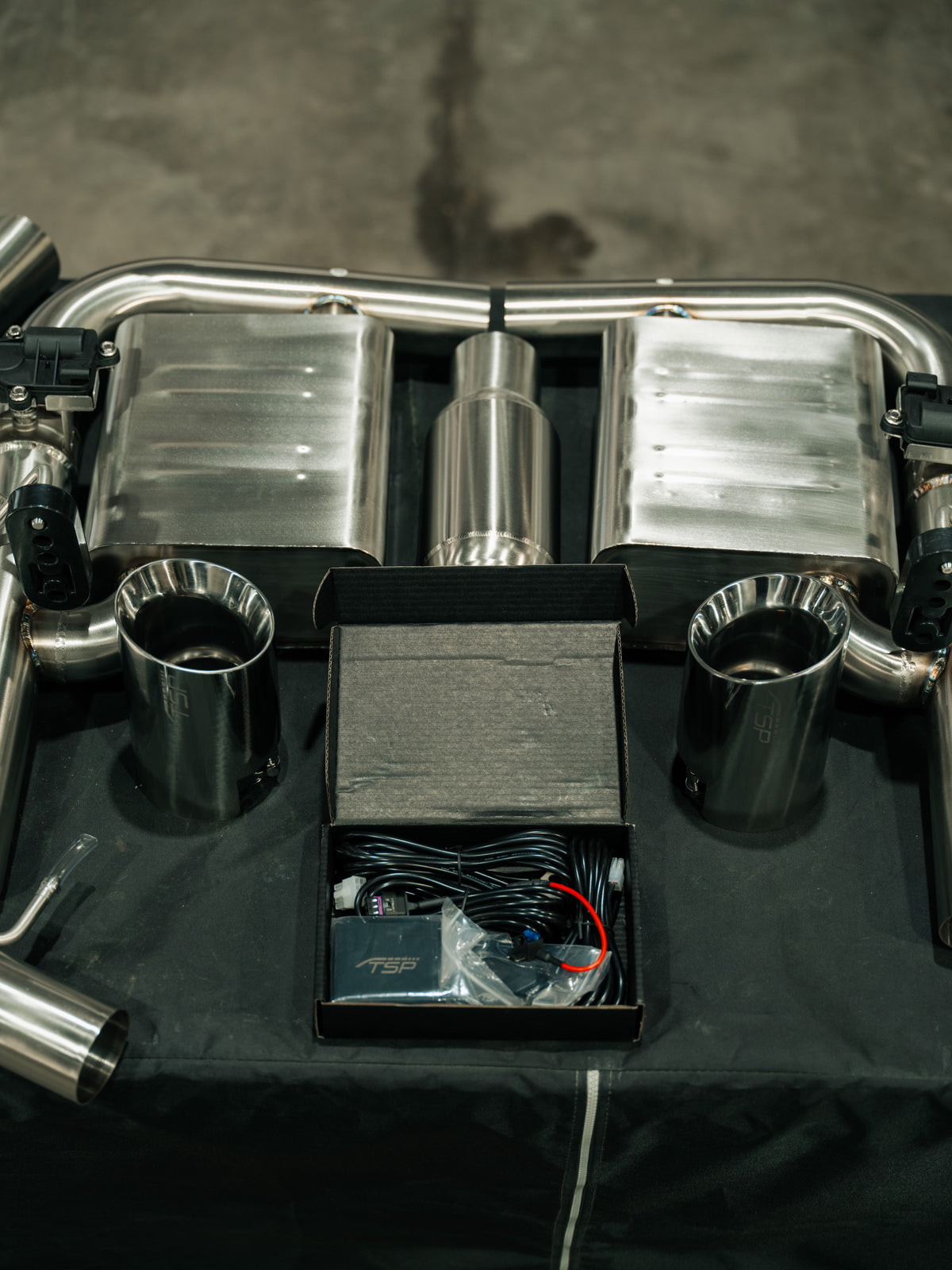 Complete TSP Hibiki exhaust system laid out showing resonated and non-resonated midpipes and the valve controller
